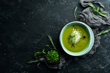 Healthy food. Green soup with broccoli and spinach in a plate on a black stone background. Top...
