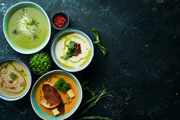 Set of colored soups in bowls on a black stone background. Healthy food. Top view. Rustic style.