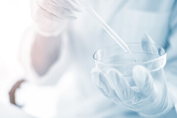 Scientist hand with rubber gloves holding a sample in Petri dish in chemical laboratory	