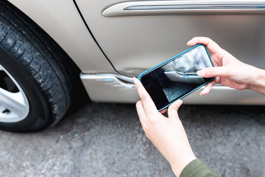 A woman using a mobile phone Take photos of the damage of the car, Which caused by a crash accident As evidence for insurance agents, to people and transportation insurance concept.