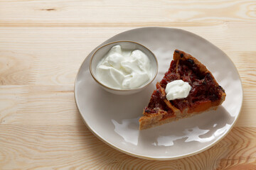 Piece of quince stuffed pie served with yoghurt. Close-up view of homemade dessert.