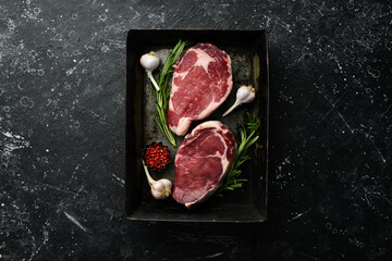 Beef steak ribeye in a metal baking dish. Top view. Free space for your text.