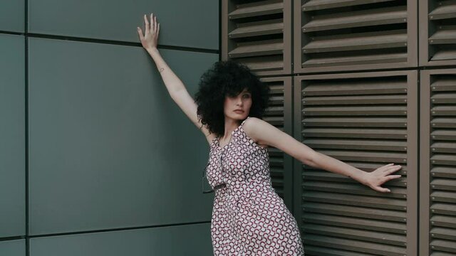 fashionable video shooting. Curly girl on the background of a wall with shutters