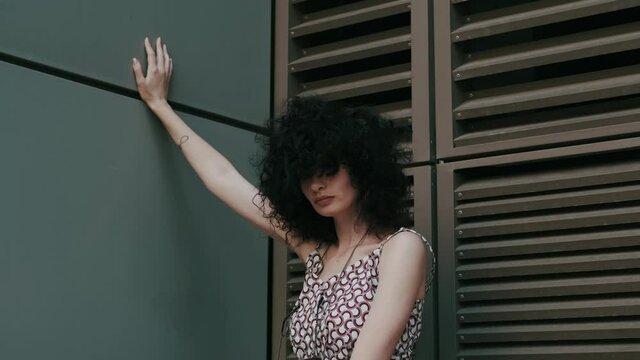 fashionable video shooting. Curly girl on the background of a wall with shutters