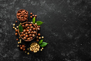 Hazelnuts in a bowl on a black stone background. Nut. free space for your text. Top view.