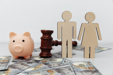 Wooden family figures, gavel and pink piggy bank on dollar banknotes, savings and divorce concept