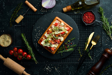Belgian waffles: with bacon, tomatoes and microgreens. Breakfast. On a black stone plate.