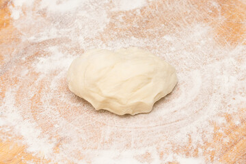 A piece of wheat dough sprinkled with flour on a cutting board.