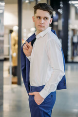 young business man holds a jacket on his shoulder and looks to the side with hand in his pocket