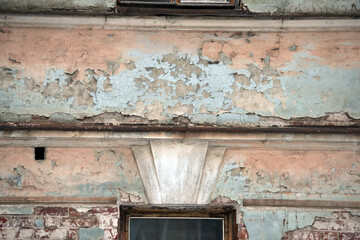 Elements of the architectural decor of the building. A fragment of the wall of an old stone house with peeling plaster.