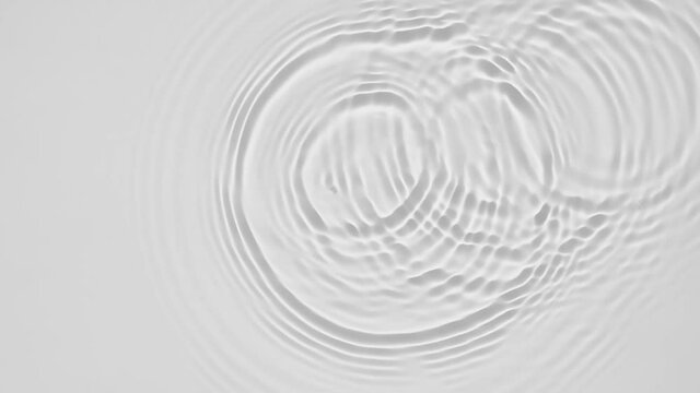 Up close, top view, Slow motion various waves of the water surface hitting the sun's rays, making them sparkle according to different patterns on a gray background video 4K.