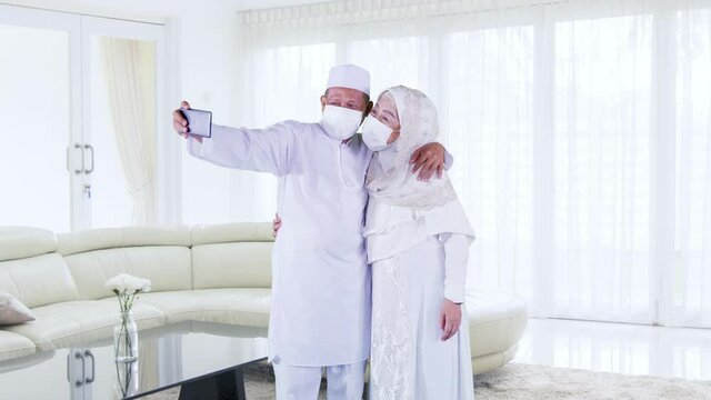 Muslim old couple in face mask take selfie at home
