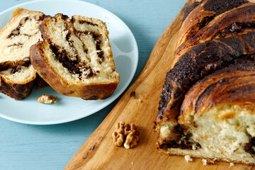 Cut piece of Krantz cake with chocolate and nuts filling. Yeast-risen dough braided cake.