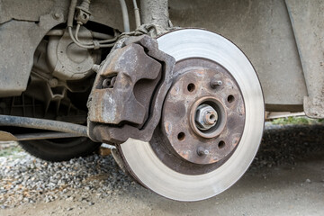 Garage repair of a passenger car. Inspection of an old brake disc in need of replacement.