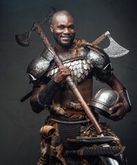 Joyful fighter with black skin holding a helmet and an axe