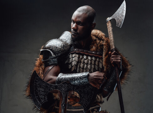 Northern african chief with fur wielding dual axes in dark background