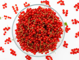 A large bowl of red currants with juicy bunches scattered around.