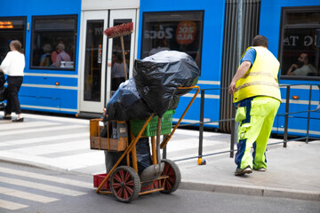 Stockholm, Sweden - June 7, 2019: Street worker in special uniform cleans the city street with tool...