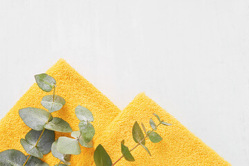 Folded yellow towels and green eucalyptus branches on a white background. SPA concept