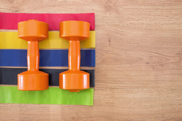 fitness rubber bands and dumbbells on a wooden background. Fitness, sport and healthy lifestyle concept.