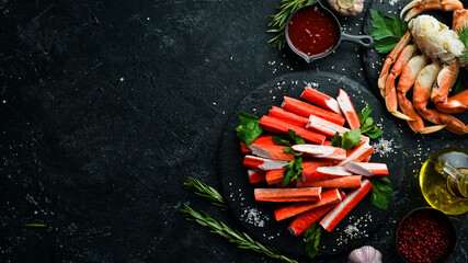 Crab sticks from a crab on a black stone plate. Rustic style. Seafood delicacies.