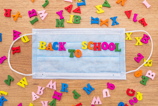 The back to school caption is lined with colored letters on a protective mask.Quarantine and lifestyle concept