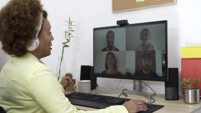 African woman teacher having video call with her students using computer app at home office - Soft focus on right hand