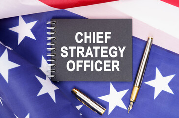 On the table is an American flag, a pen and a notebook with the inscription - CHIEF STRATEGY OFFICER