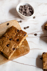 Top of view of homemade blond brownie. Blondie with a bowl full of chocolate chips. Vertical.