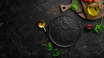 Vegetables, spices and herbs on a black stone background. Kitchen background. Top view. Free space...