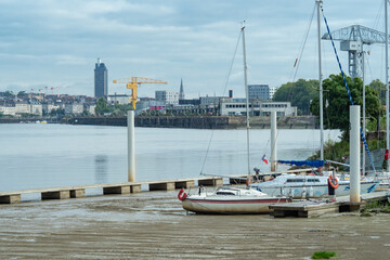 Fototapeta na wymiar Sailboats lying on ground at low tide in front of the harbour of Nantes, France