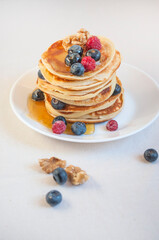 Freshly cooked delicious pancakes with honey, walnut, raspberries and blueberries for breakfast.
