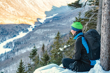 Fototapeta na wymiar Woman hiker sitting at the top of the snowy valley, Jacques Cartier national park, QC, Canada