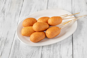Corn dogs on white serving plate