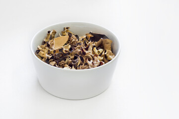Close up of a white bowl filled with scented dry natural leaves or potpourri.