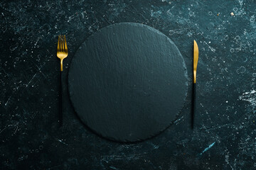 Table setting. Slate black stone plate with cutlery. Top view. Free copy space.