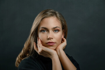 Fototapeta premium beautiful young blonde girl close up in black clothes on a black background. portrait of a beautiful elegant woman