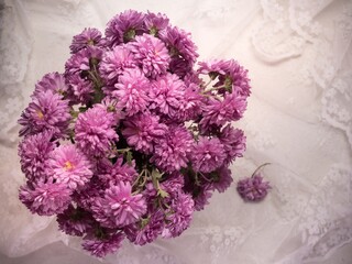 A bouquet of pink chrysanthemums on a delicate white tablecloth
