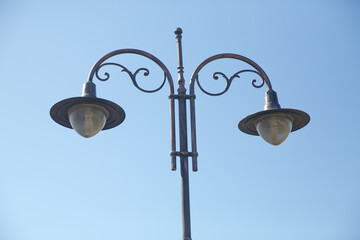 Vintage street light.black street lamp in an open blue sky . Street lantern on background blue sky . Old street light.