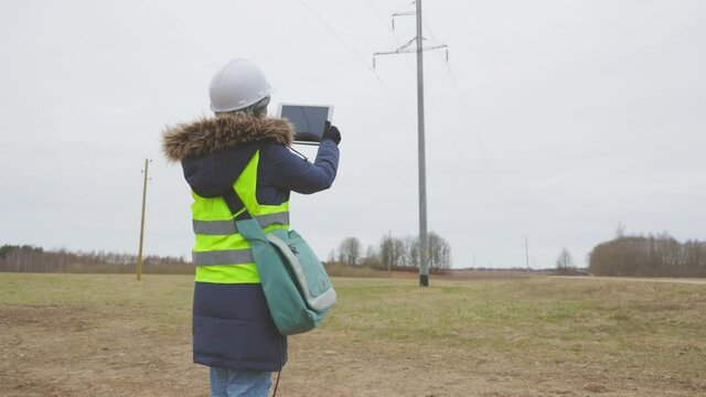 Woman electrical engineer taking photos of high voltage line