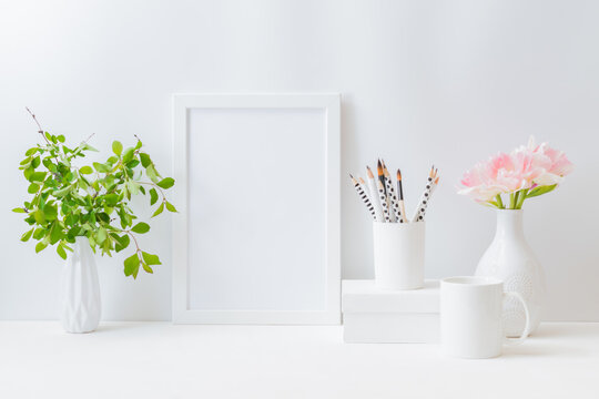 Home interior with decor elements. Mockup with a white frame and pink tulips in a vase on a light background