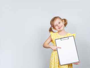 Little Caucasian girl holding a clipboard with a blank paper with copy space