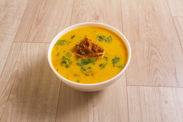 Indian Cuisine pakoda Kadhi - Vegetarian Curry Made of Buttermilk And Chick Pea Flour. served in a bowl over wooden background, selective focus