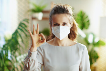 smiling trendy woman in grey blouse showing ok gesture