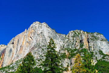 Fototapeta na wymiar Tall Rocky Mountain peak reaching above the green forest into the blue sky.