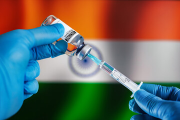 Preparing dose of vaccine in syringe for infections prevention in front of the Indian flag. Doctor preparing vial of vaccine injection for the vaccination plan against diseases in India