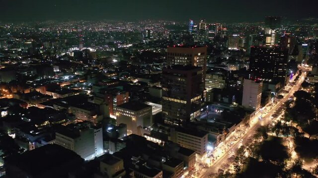 Flying over Mexico City lit up at night with downtown cityscape skyline, Aerial