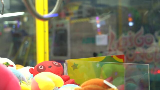 Carnival lights sparkle through the glass of a claw game.