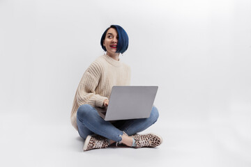 A woman sitting on the floor and holding a laptop