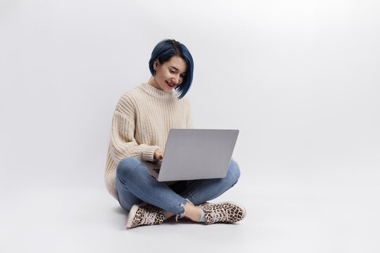 A Woman Sitting On The Floor And Holding A Laptop